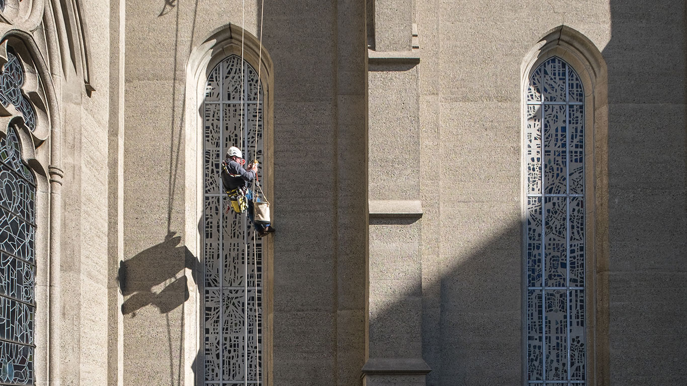 Rope access technician inspecting window sealant.